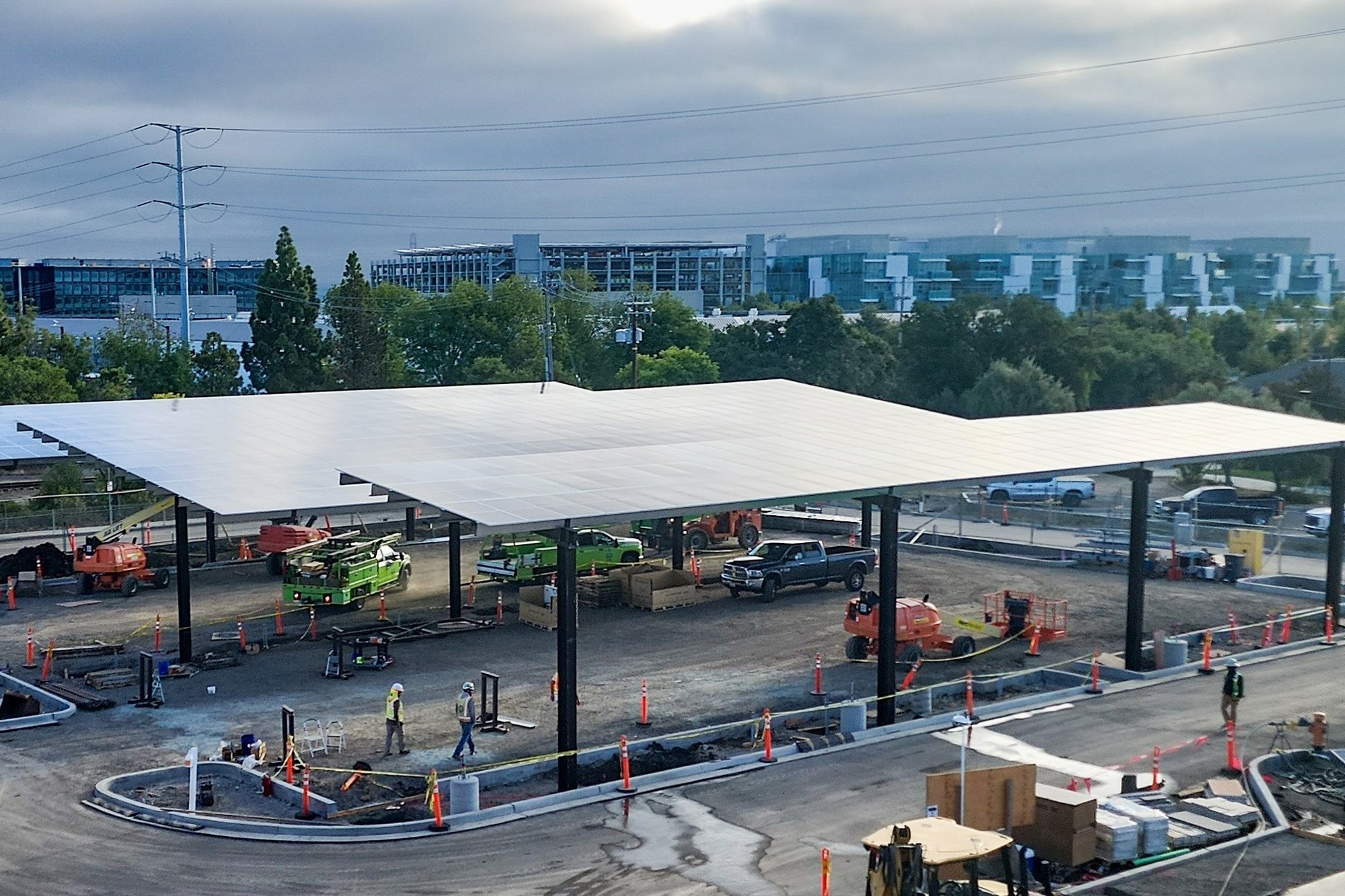 Solar canopy installation under construction at a municipal facility in the City of Menlo Park, with crews, equipment, and vehicles working beneath newly installed panels.
