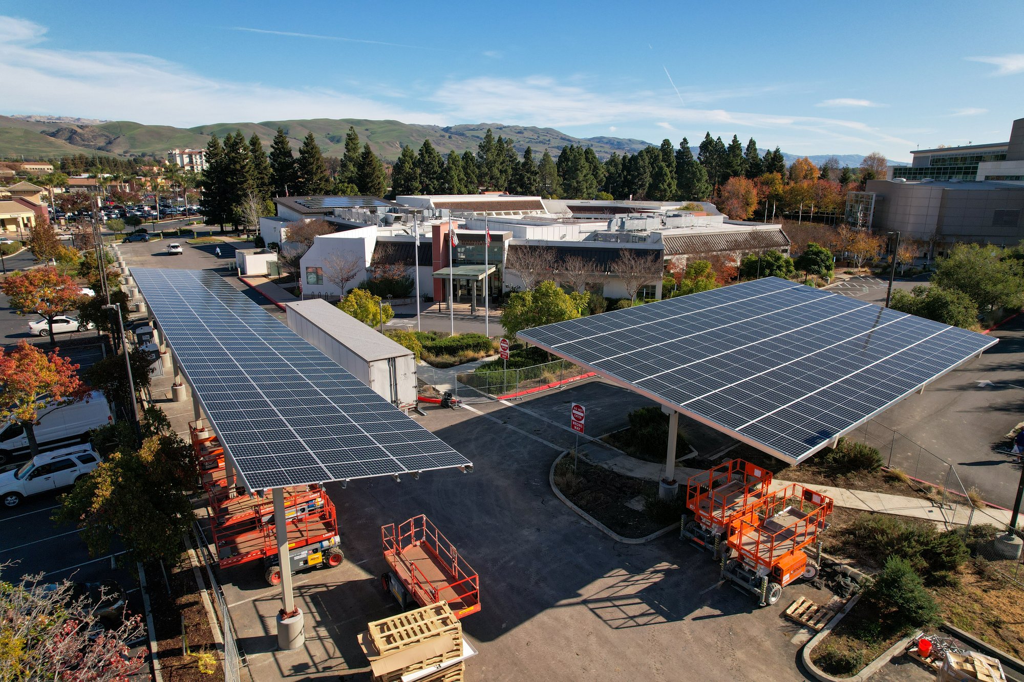 Aerial view of solar canopy installations and construction equipment at a municipal facility in the City of Milpitas, showcasing ongoing microgrid and solar infrastructure development.