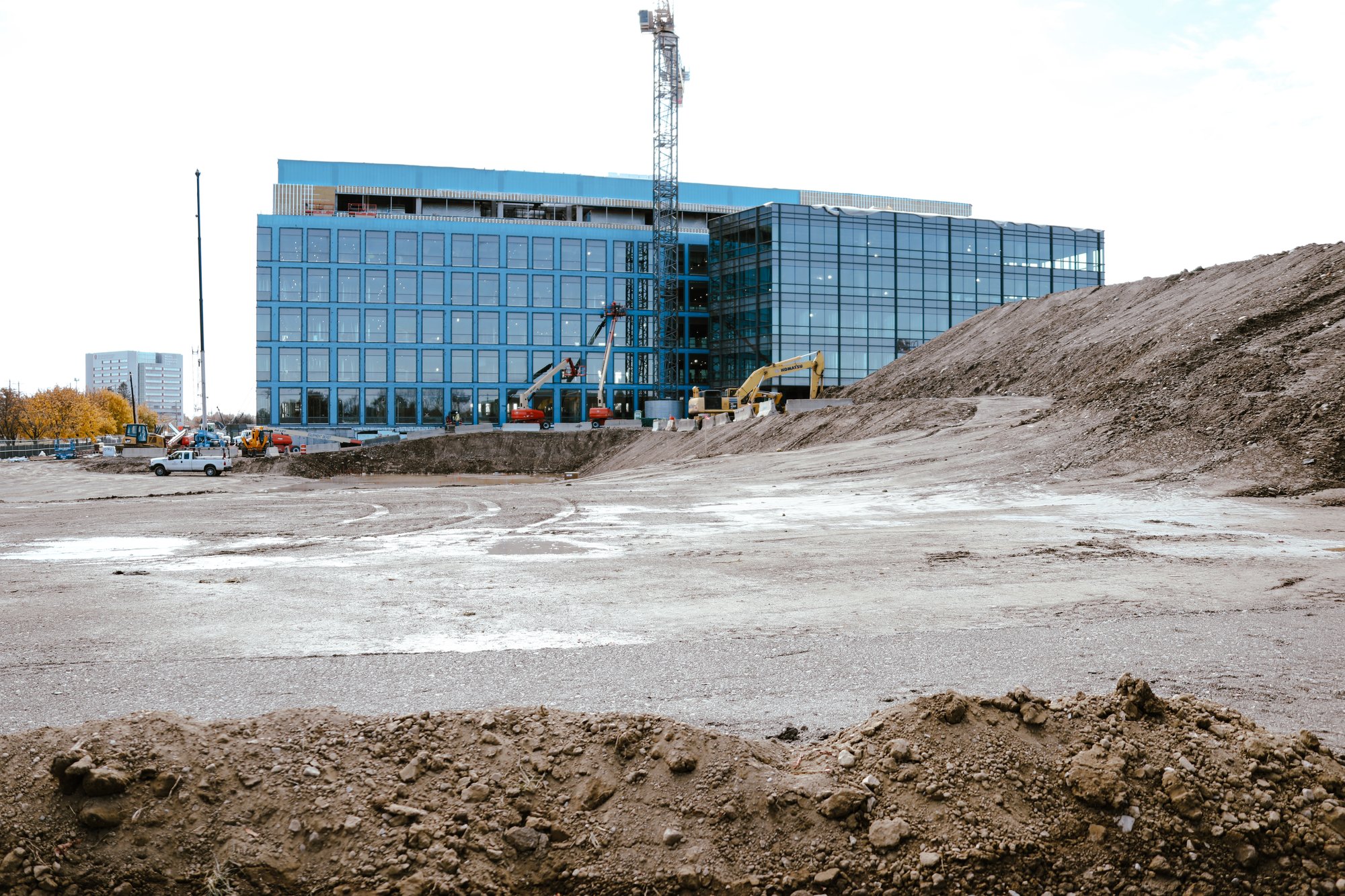 Construction site at The Ohio State University during the groundbreaking of the Innovation Center, with earthmoving equipment and a modern glass building in the background.