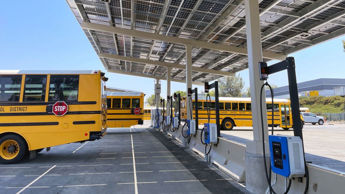 Electric school buses charging at a San Marcos Unified School District depot beneath a solar carport, showcasing clean transportation infrastructure.