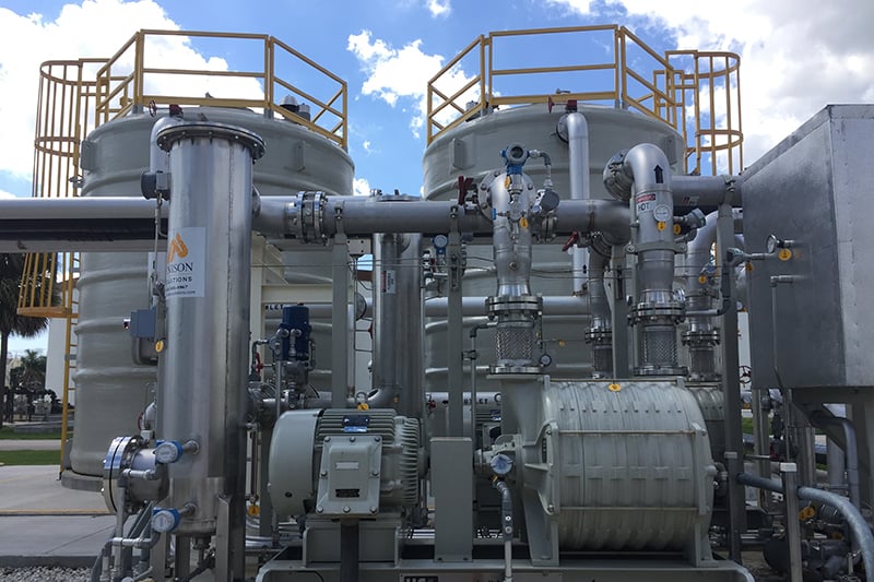 Industrial central utility plant equipment with pumps, piping, tanks, and process infrastructure at a wastewater treatment facility.