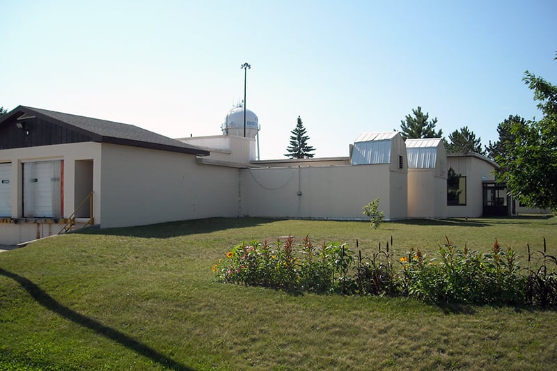 Exterior view of Kinross facility with landscaped grounds, a low-rise building, and a central tower.