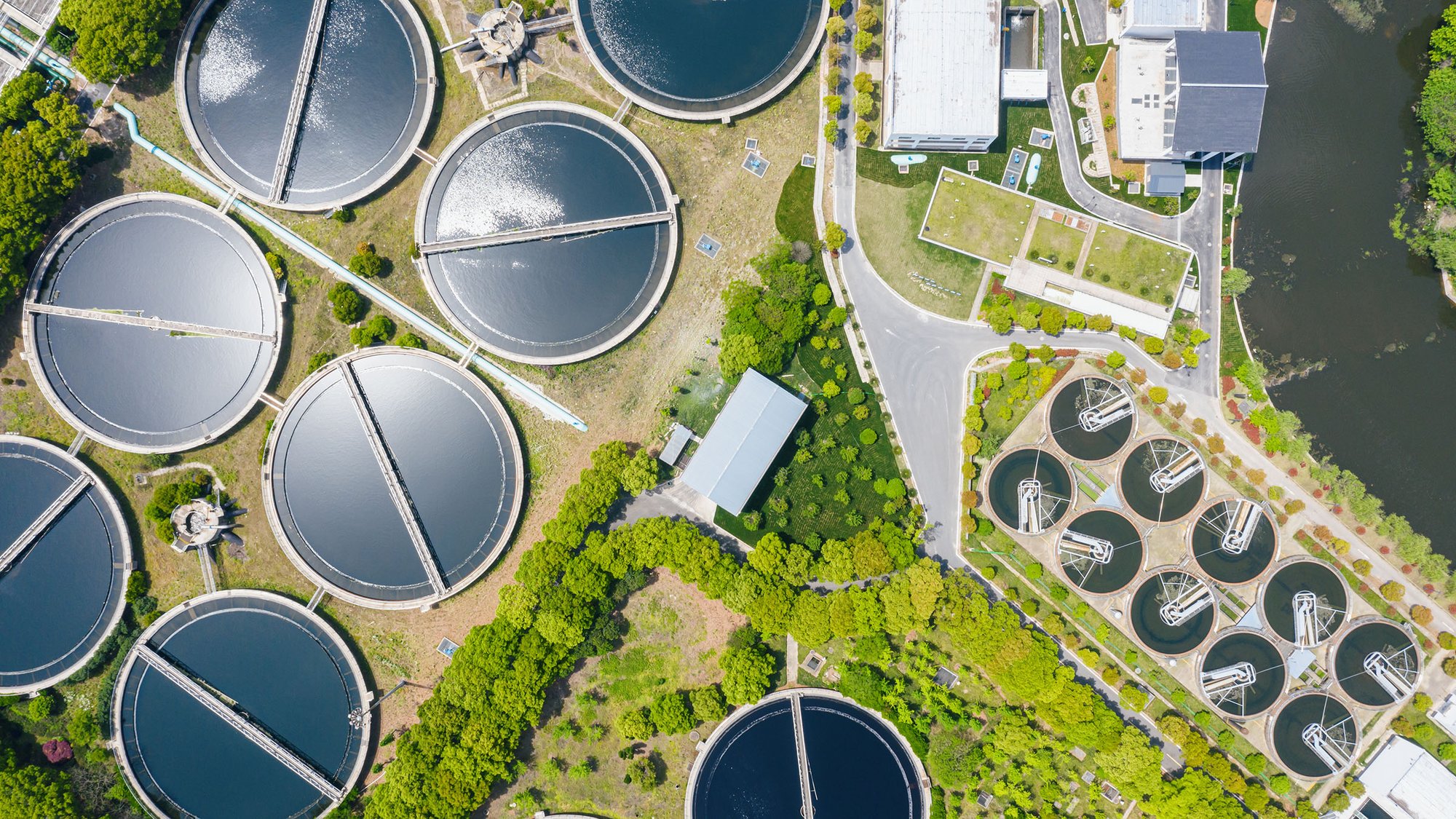 Aerial view of a wastewater treatment plant with clarifiers and basins.